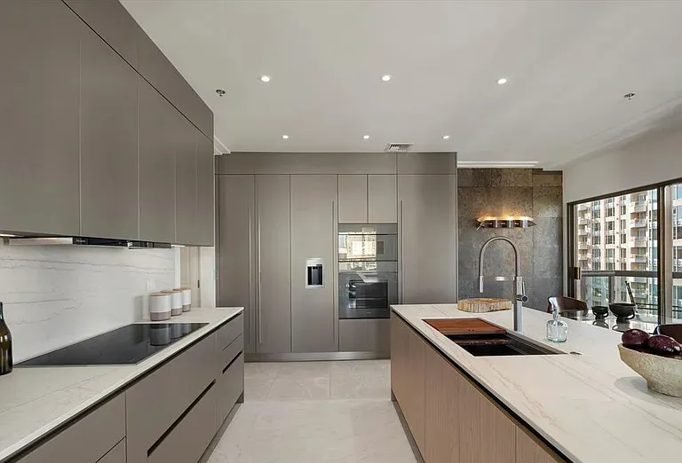 Kitchen with gray tall cabinets, built-in appliances, and a light wood island