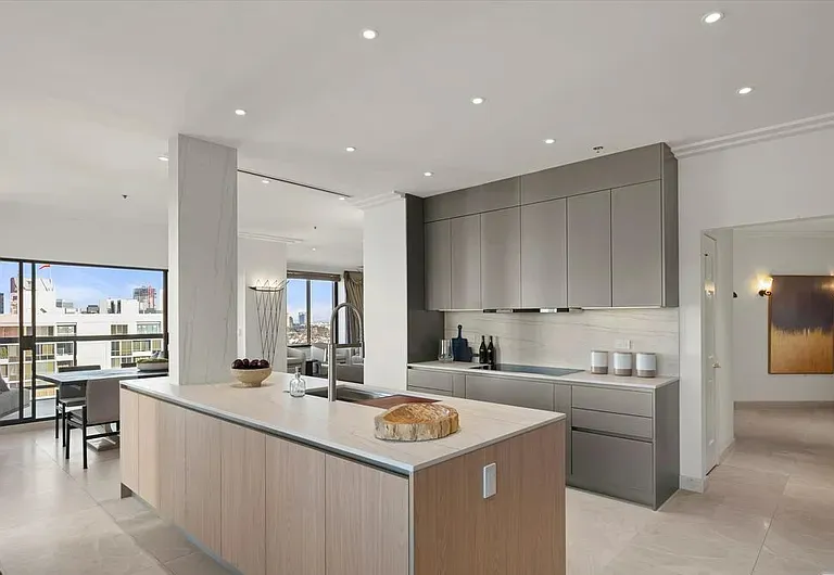 Light wood kitchen island and gray cabinetry with city views