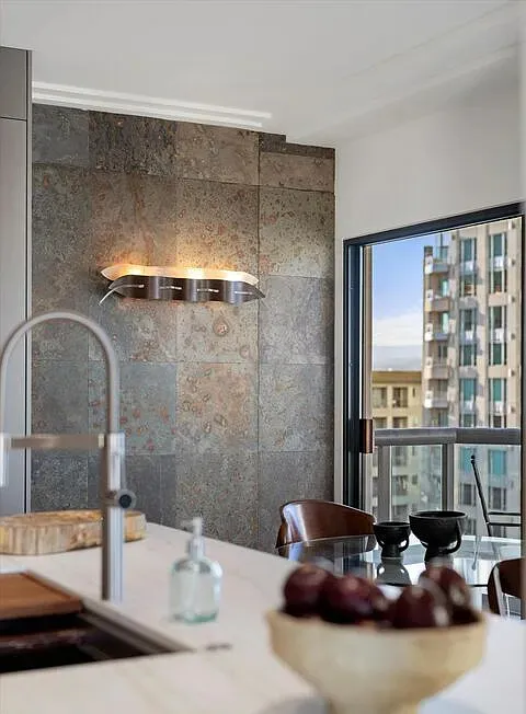 Kitchen faucet and stone wall with sconces near a window