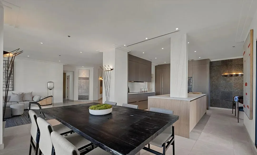 Dining table in front of the kitchen island and stone wall