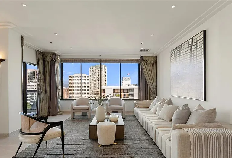 Living room with cream sofas and city views at dusk