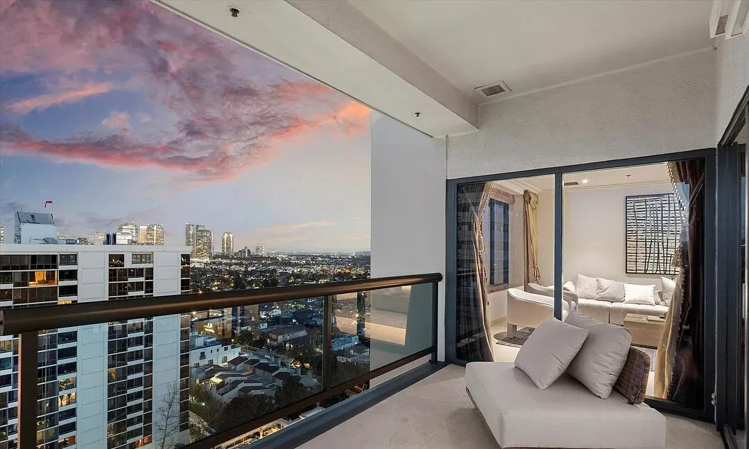 Balcony with lounge seating overlooking the city at sunset