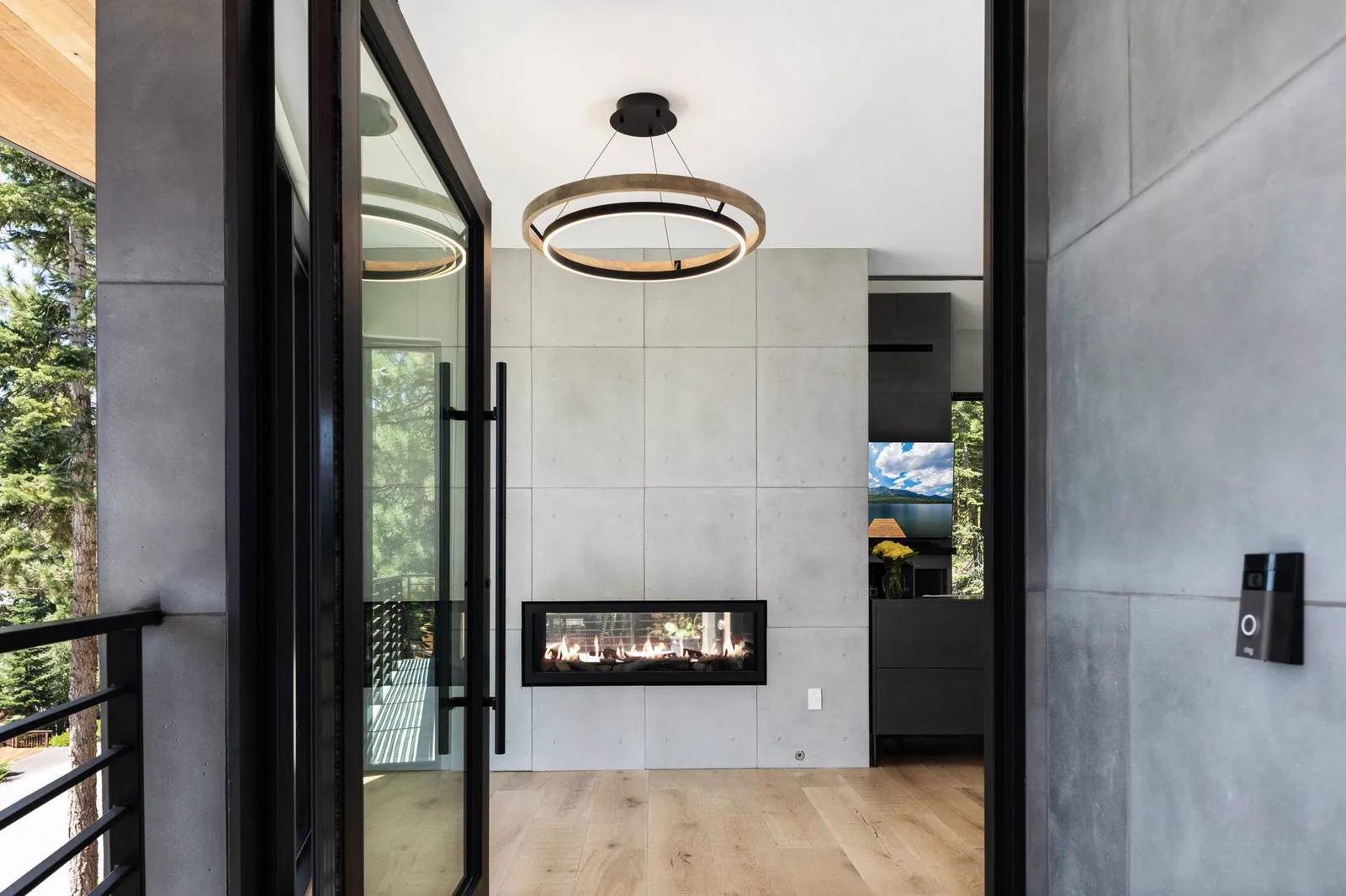 Entry with a glass door, round pendant, and a fireplace set in a concrete wall