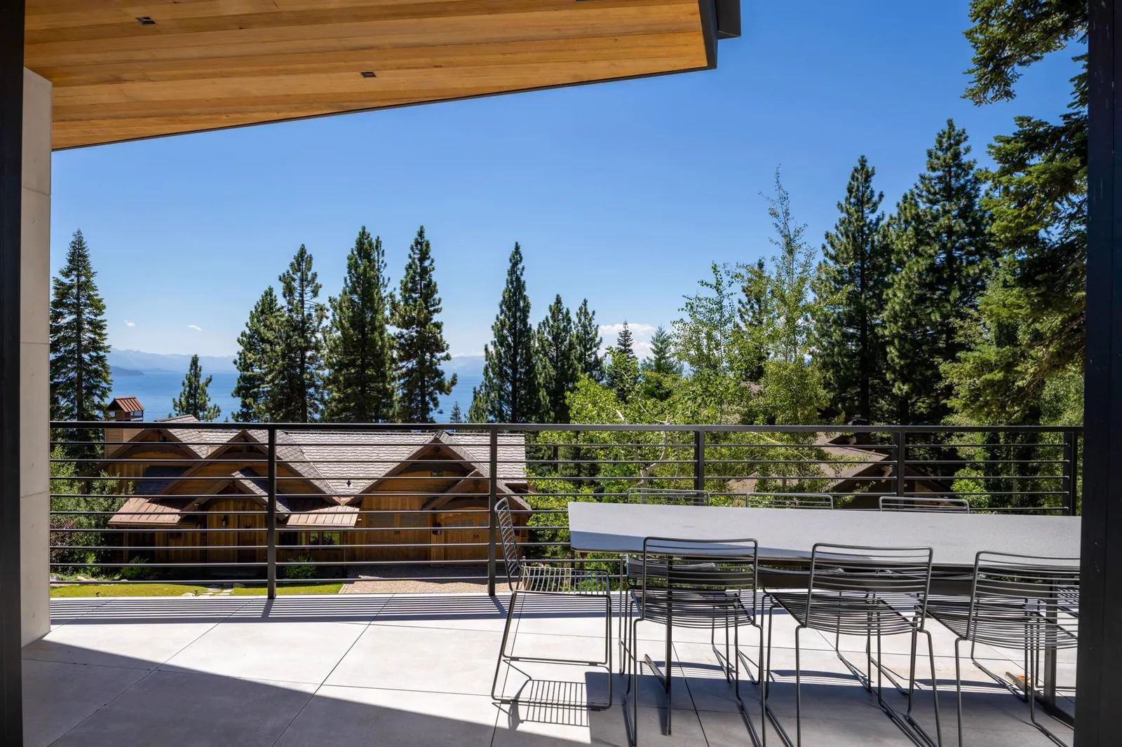 Deck with a dining table overlooking the lake through pine trees
