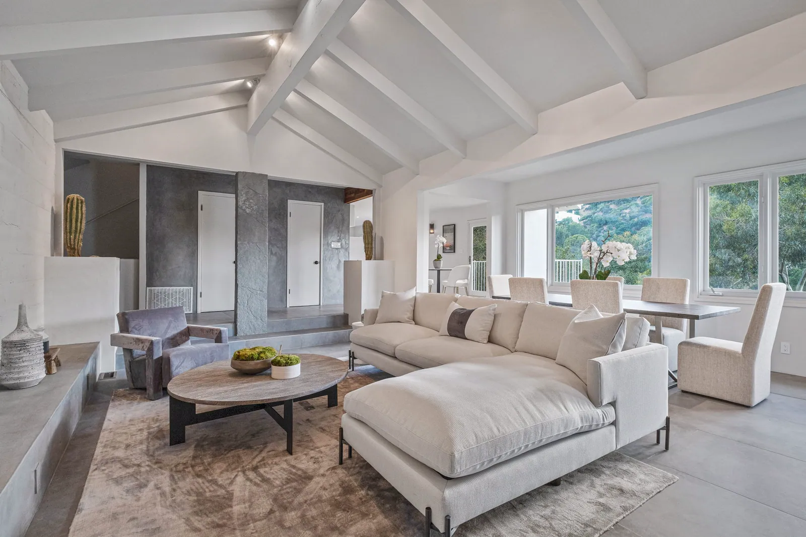 Living room with a vaulted white beamed ceiling, a sectional sofa, and canyon views