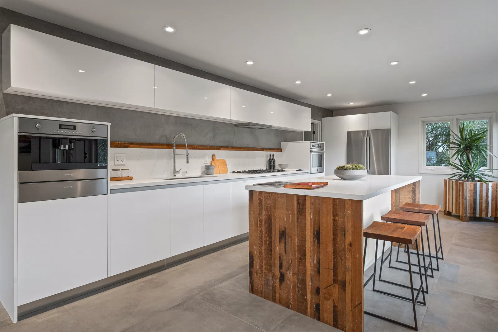 White kitchen with a long run of flat-panel cabinets and an island clad in dark wood