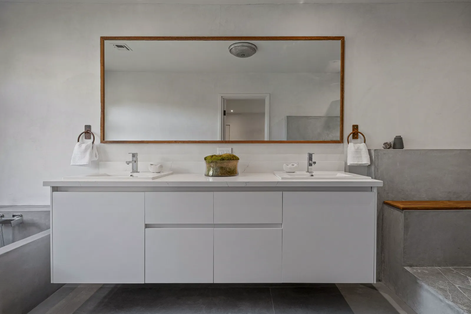 Bathroom with a floating white double vanity and a wood-framed mirror