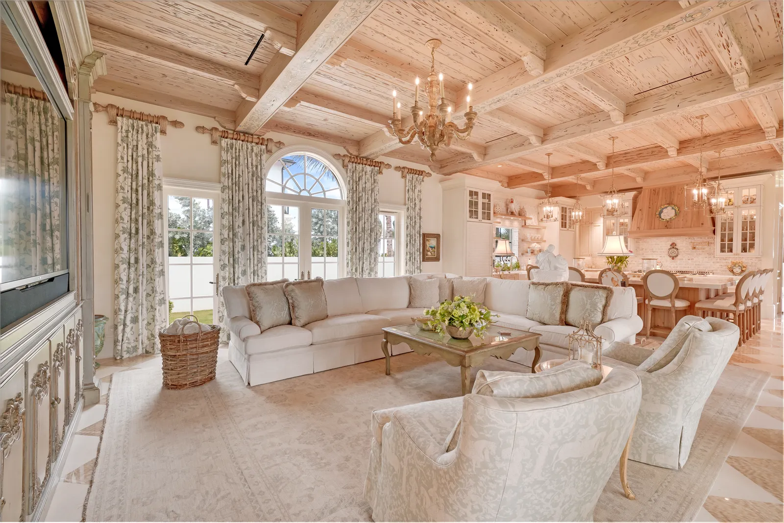 Family room under a pecky cypress coffered ceiling with white sofas and arched windows
