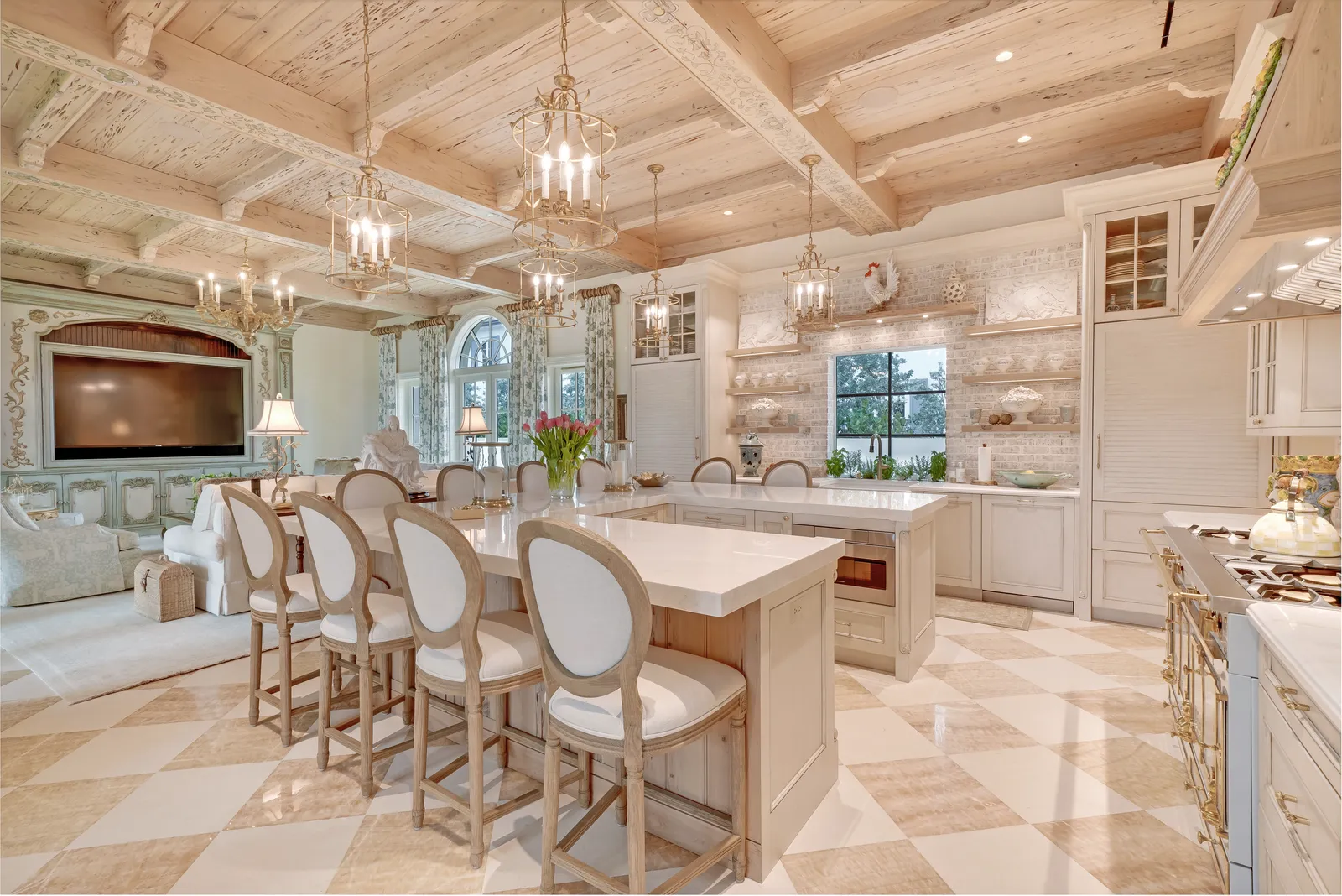 Kitchen island with upholstered counter chairs and the family room beyond