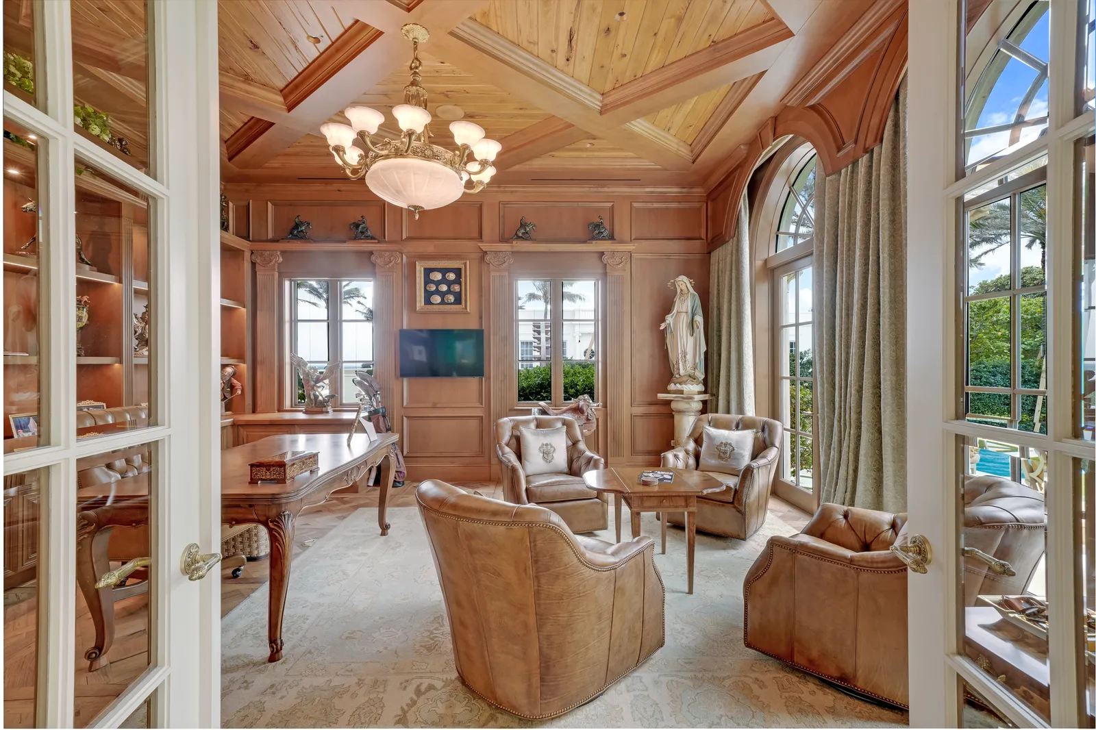 Seating area in the wood-paneled office with leather armchairs and French doors