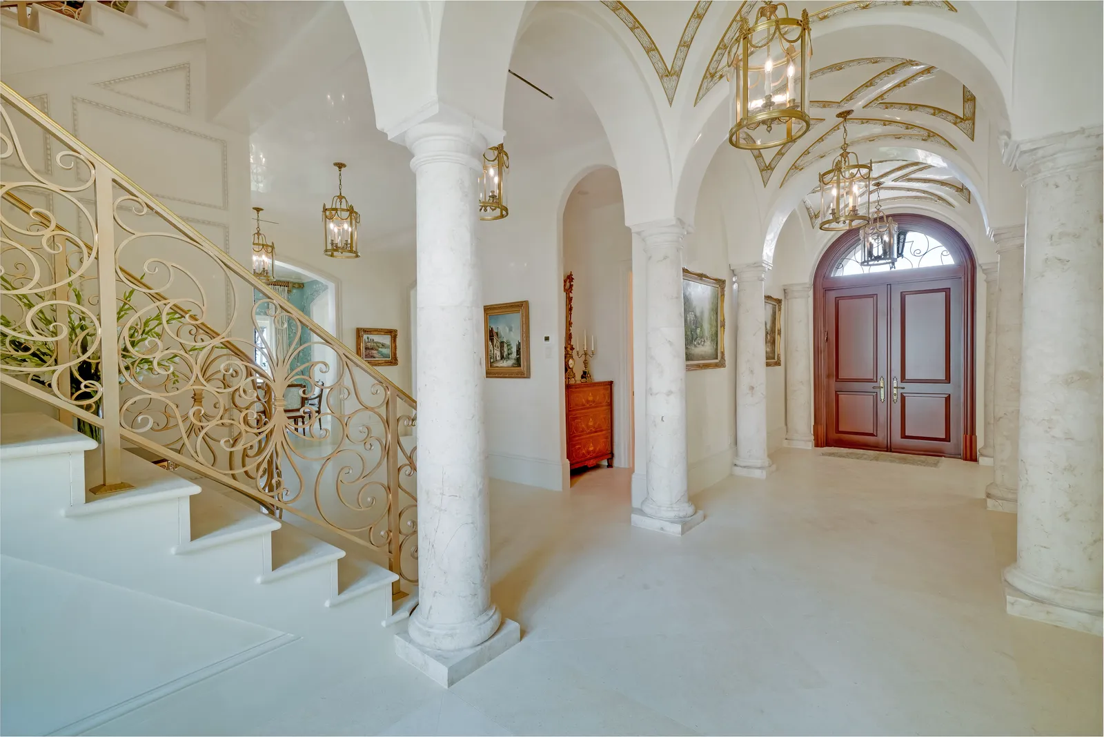 Entry hall with vaulted ceilings, columns, lanterns, and an arched wood front door