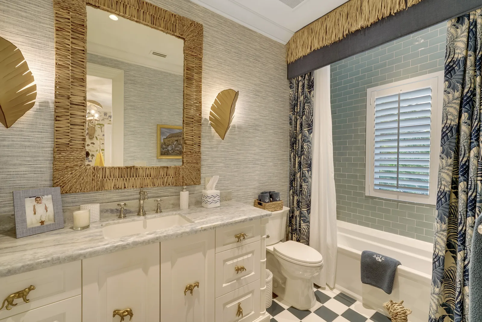 Bathroom with a white vanity, rattan mirror, and checkered floor