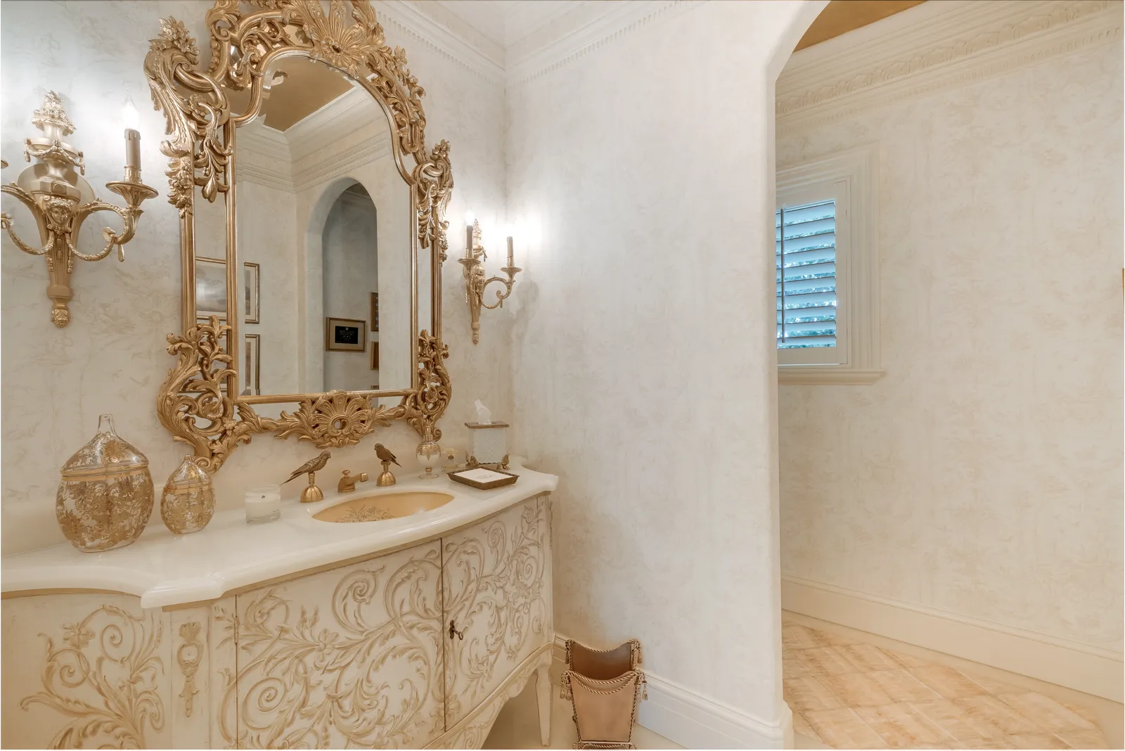 Powder room with a carved stone vanity and gilded mirror