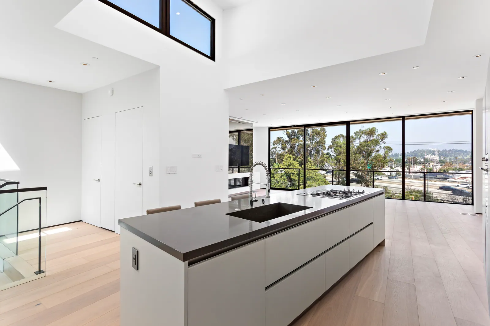 White kitchen island with a dark countertop facing a wall of windows with city views