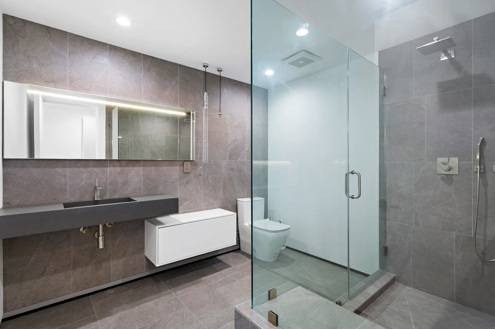 Bathroom with gray stone-look walls, a floating vanity, and a frameless glass shower