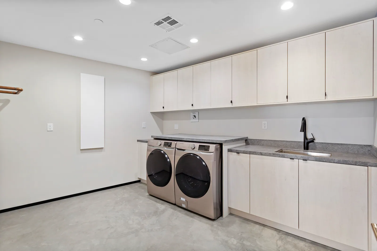 Laundry room with white cabinets and front-loading washer and dryer