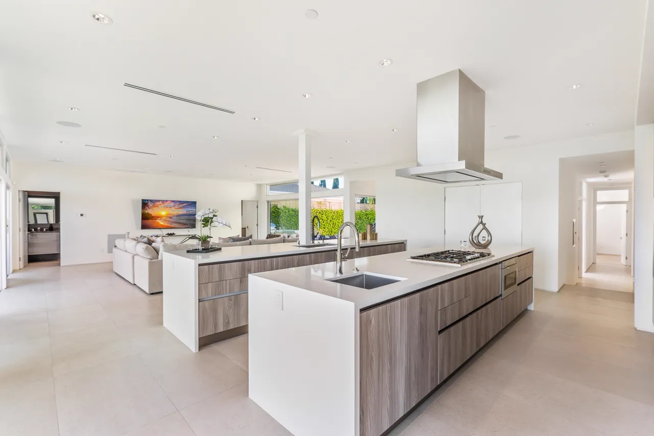 Kitchen with two islands and a stainless hood, with the family room beyond