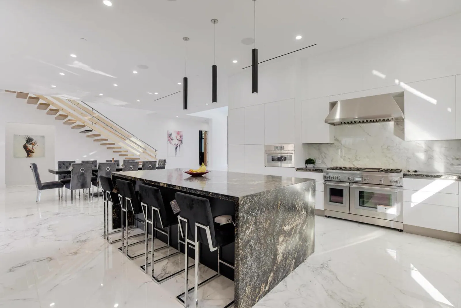 Kitchen with a granite island and bar stools, a professional range, and a floating stair beyond