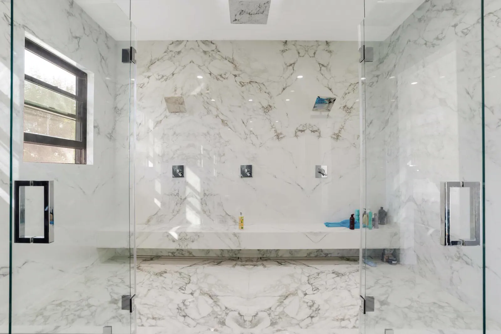 Shower with marble walls and a long bench