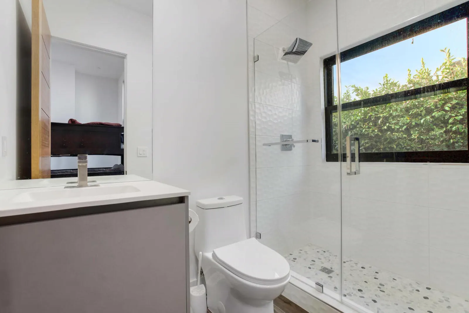 Bathroom with a floating vanity and a glass shower beside a wide window