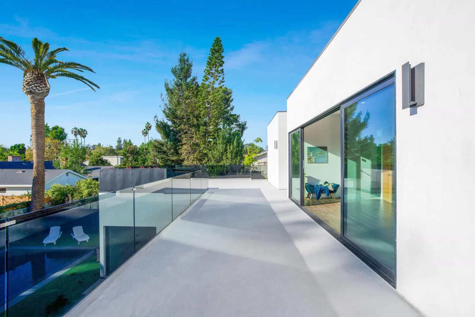 Upper terrace with a glass railing overlooking the pool and palm trees