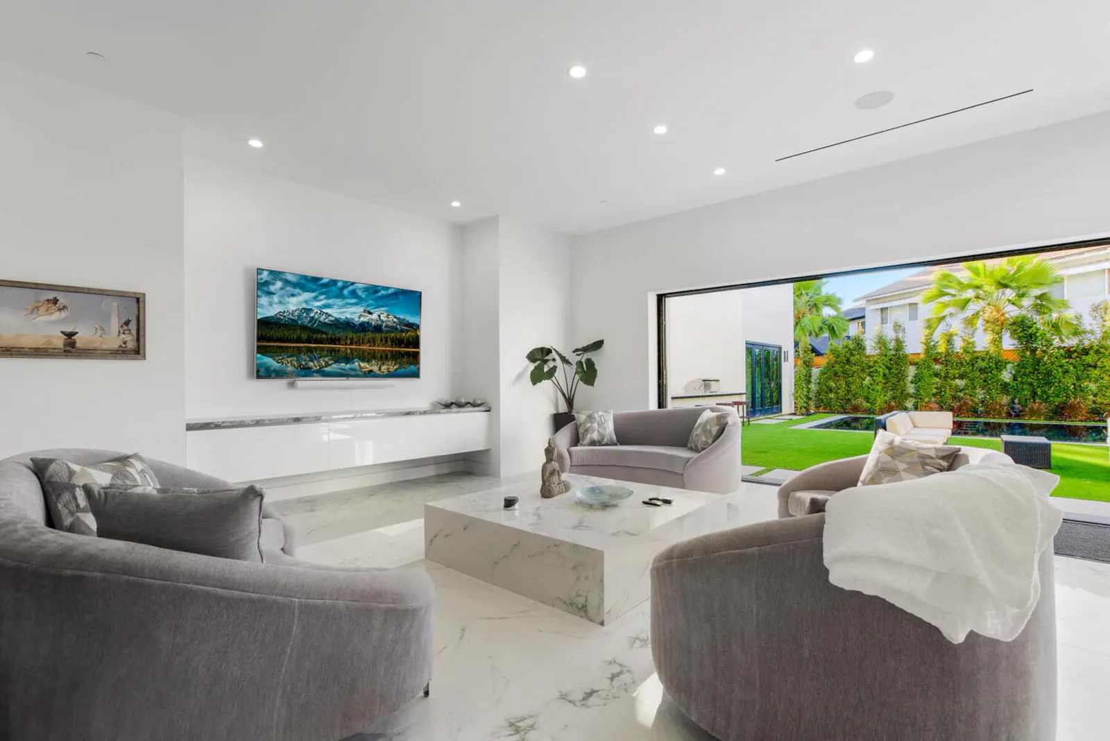 Living room with gray armchairs and a wall of glass to the garden