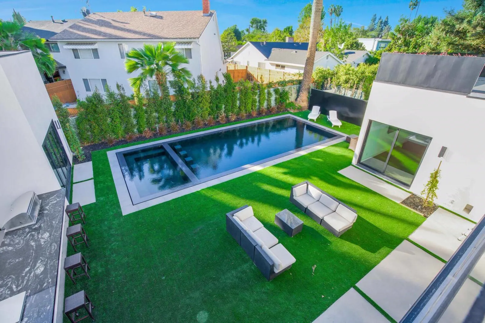 Aerial view of the backyard with a lap pool, lawn, and lounge seating