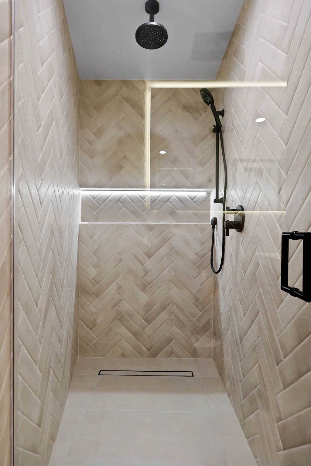 Walk-in shower with herringbone tile and a lit niche