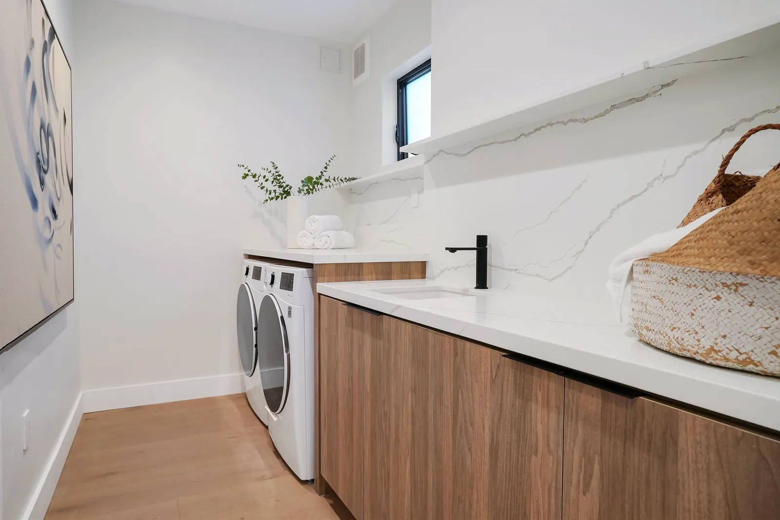Laundry room with walnut cabinets and a white marble-look counter and backsplash