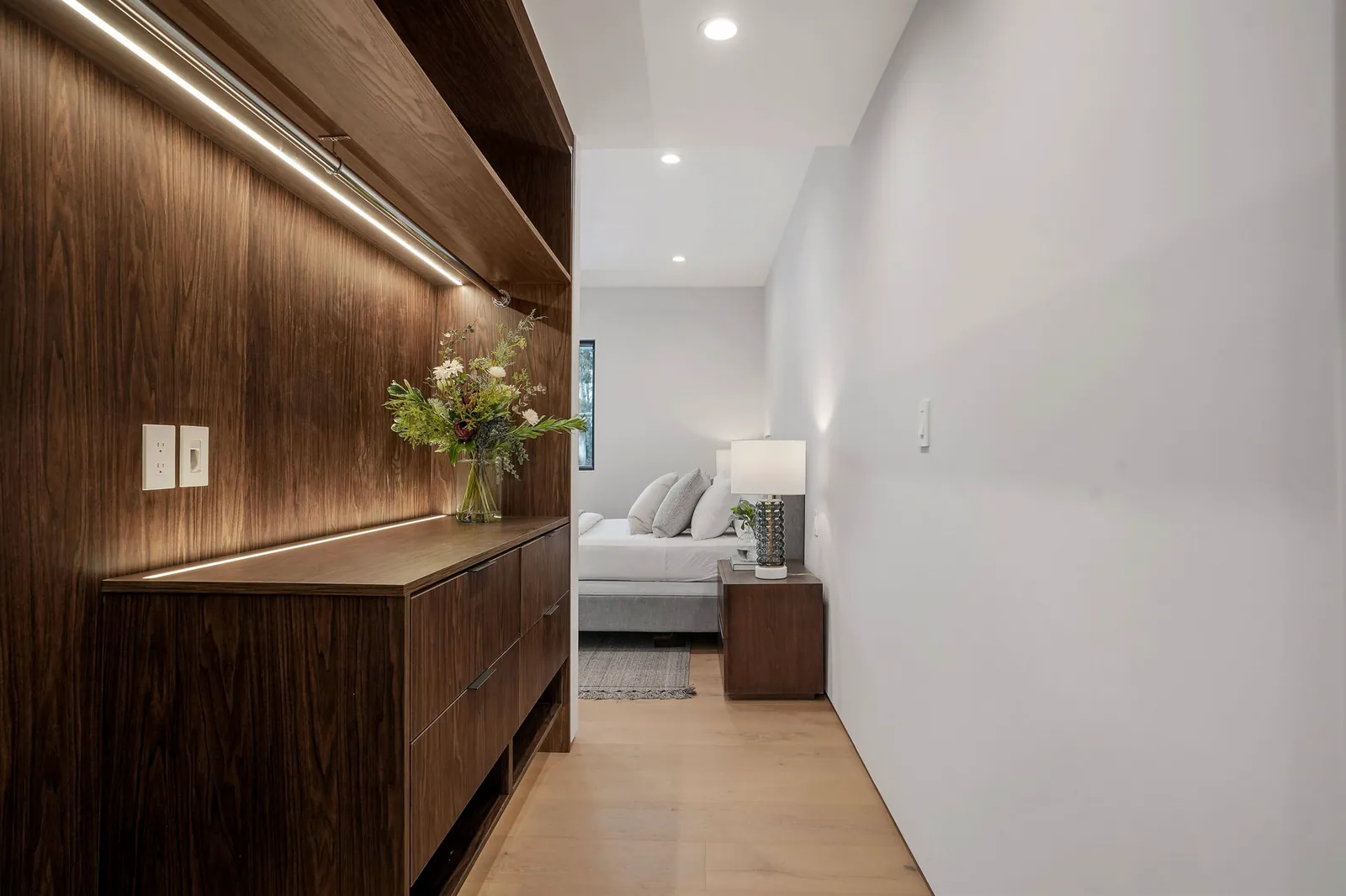 Walnut cabinetry wall with integrated lighting leading to a bedroom