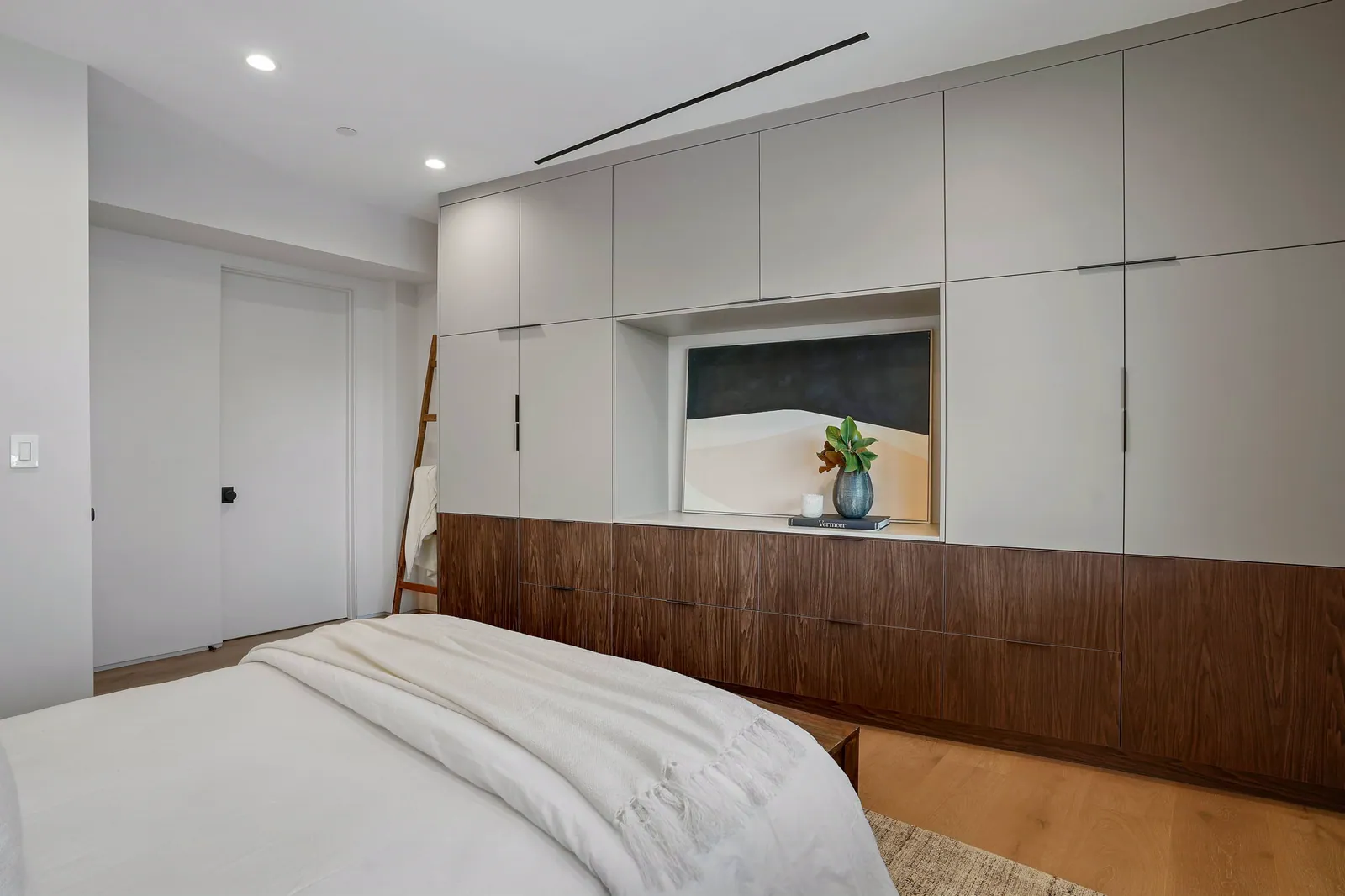 Bedroom with a built-in white and walnut storage wall around a window