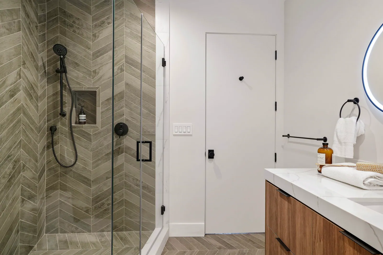Bathroom with a herringbone tile shower and walnut vanity