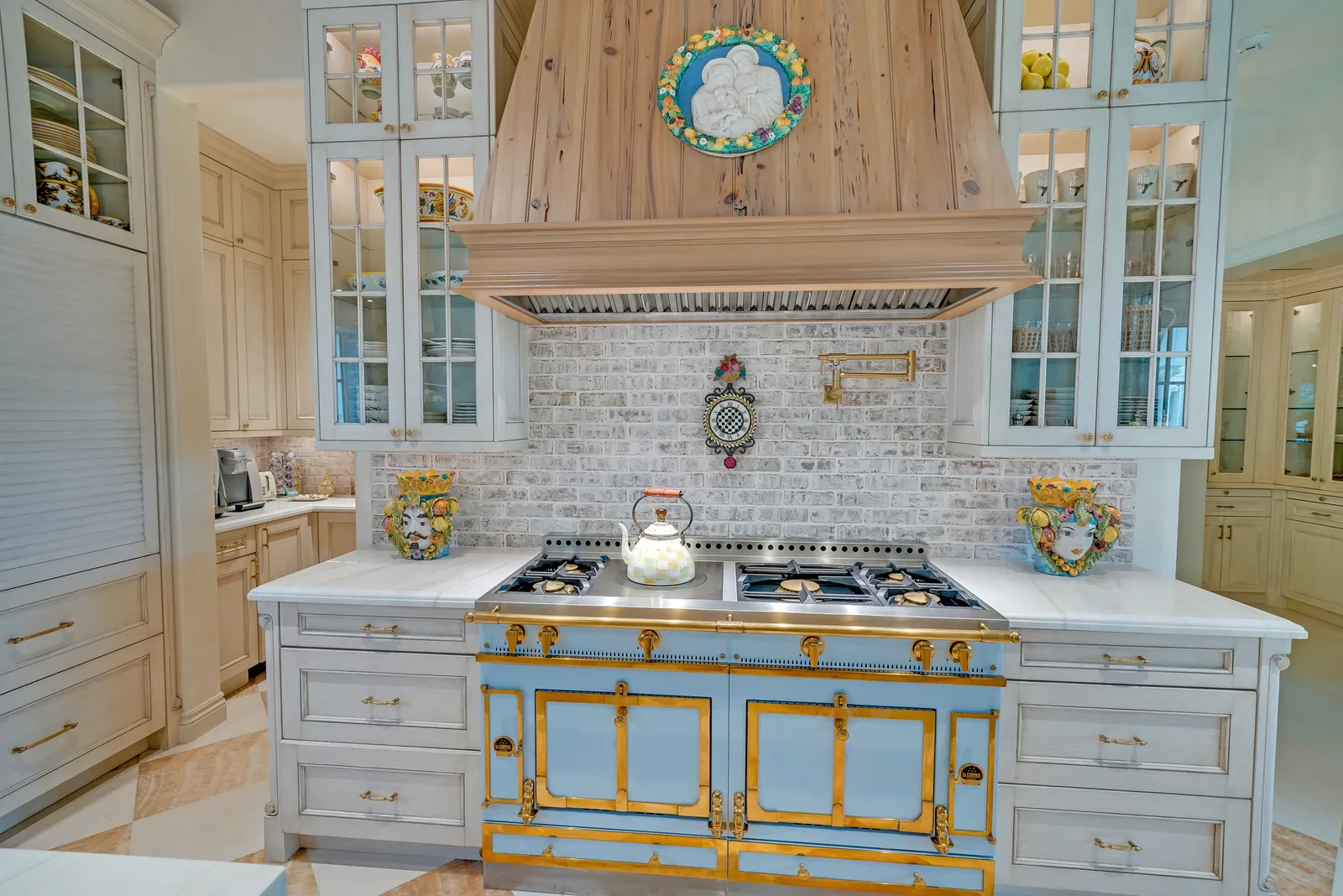 Range wall with a blue and brass La Cornue range, tile backsplash, and glass-front cabinets
