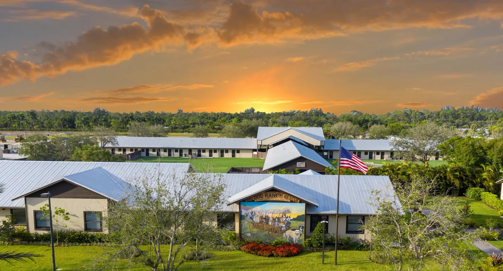 Campus buildings at sunset with a painted mural and a flagpole