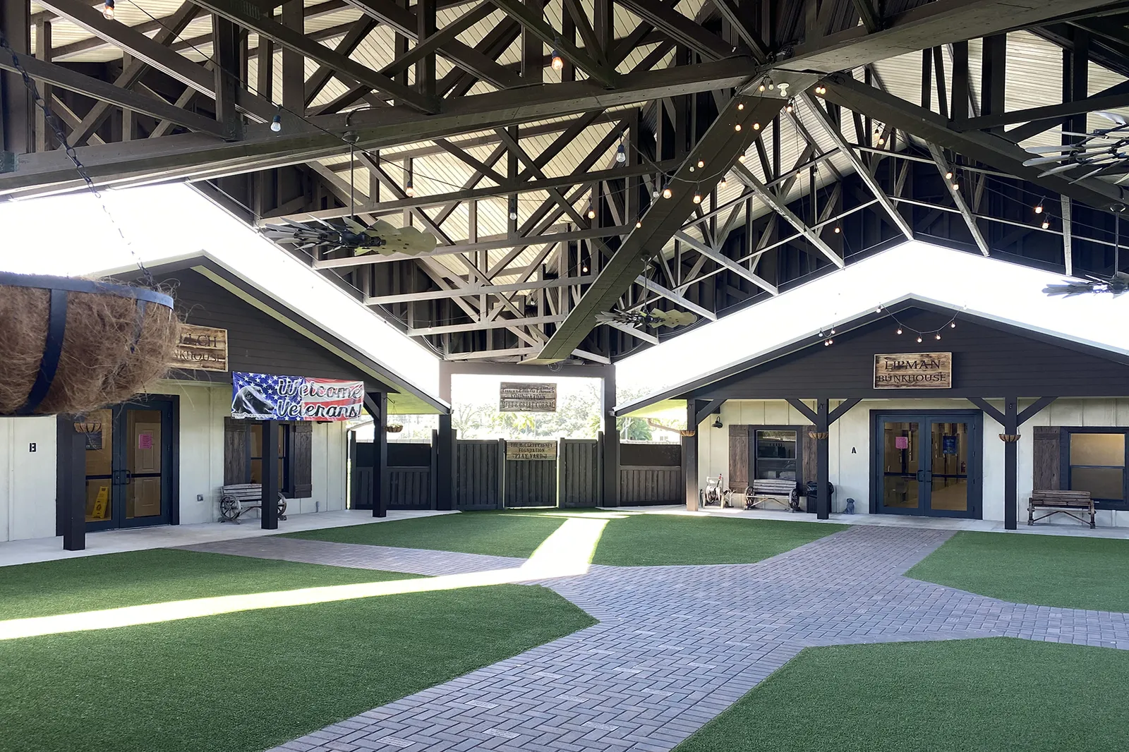 Covered open-air pavilion with timber trusses and artificial turf