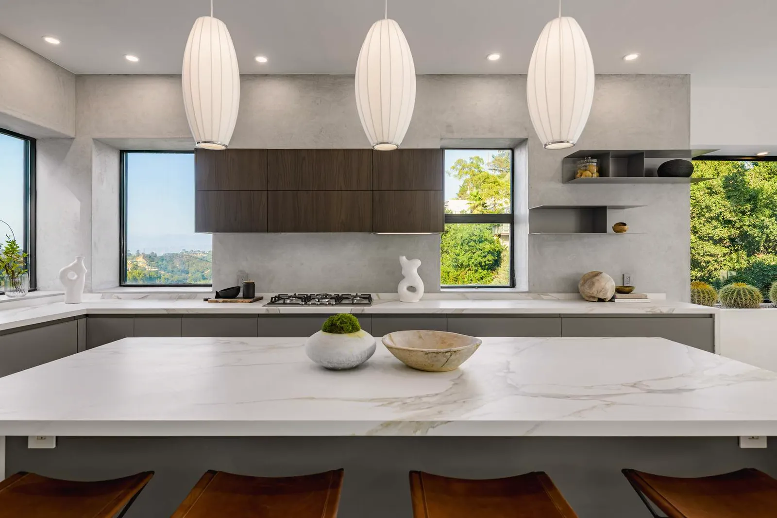 Marble kitchen island under three paper pendant lights with dark wood cabinets beyond