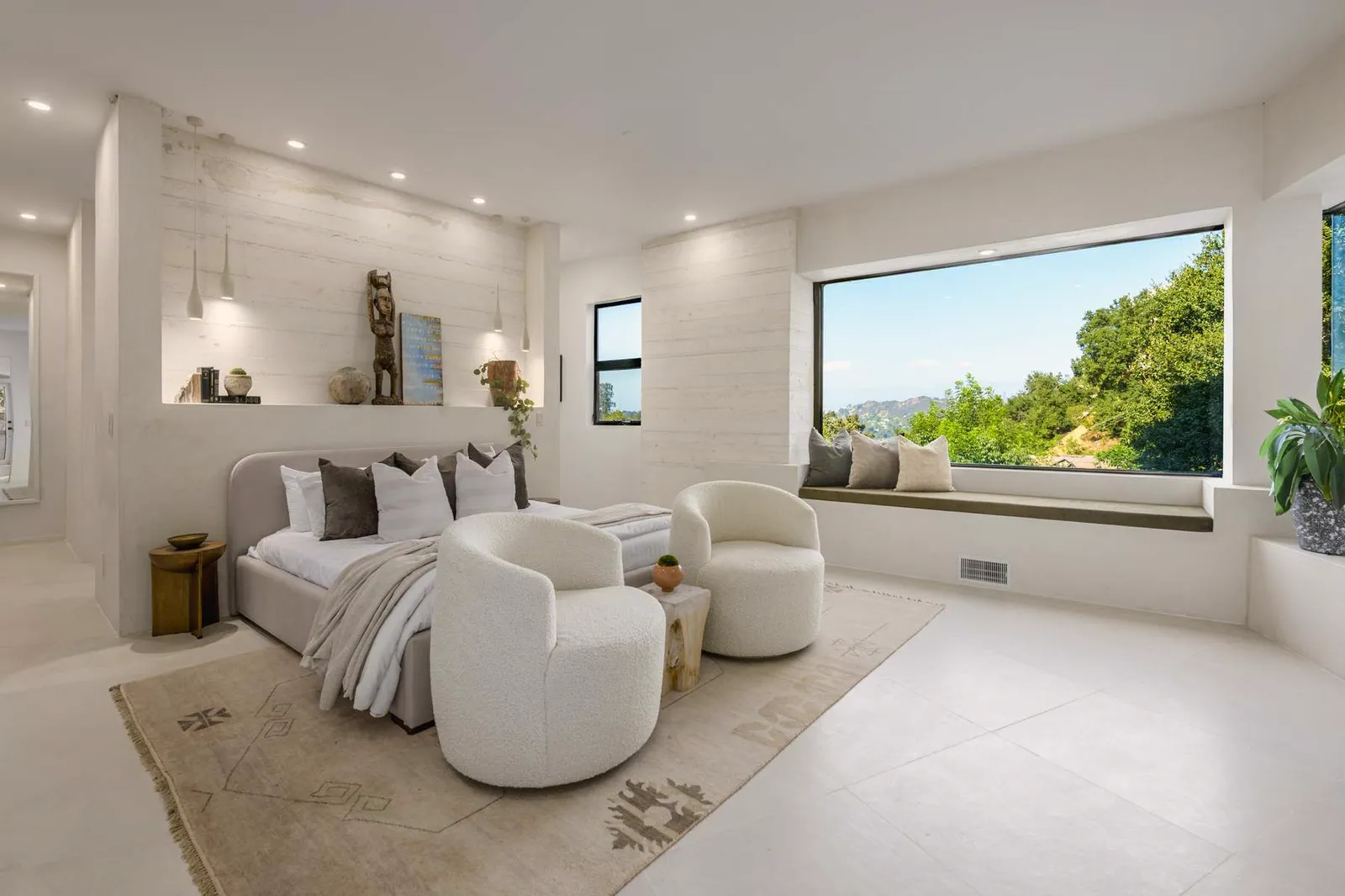 Bedroom with a curved armchair and a window seat facing the trees