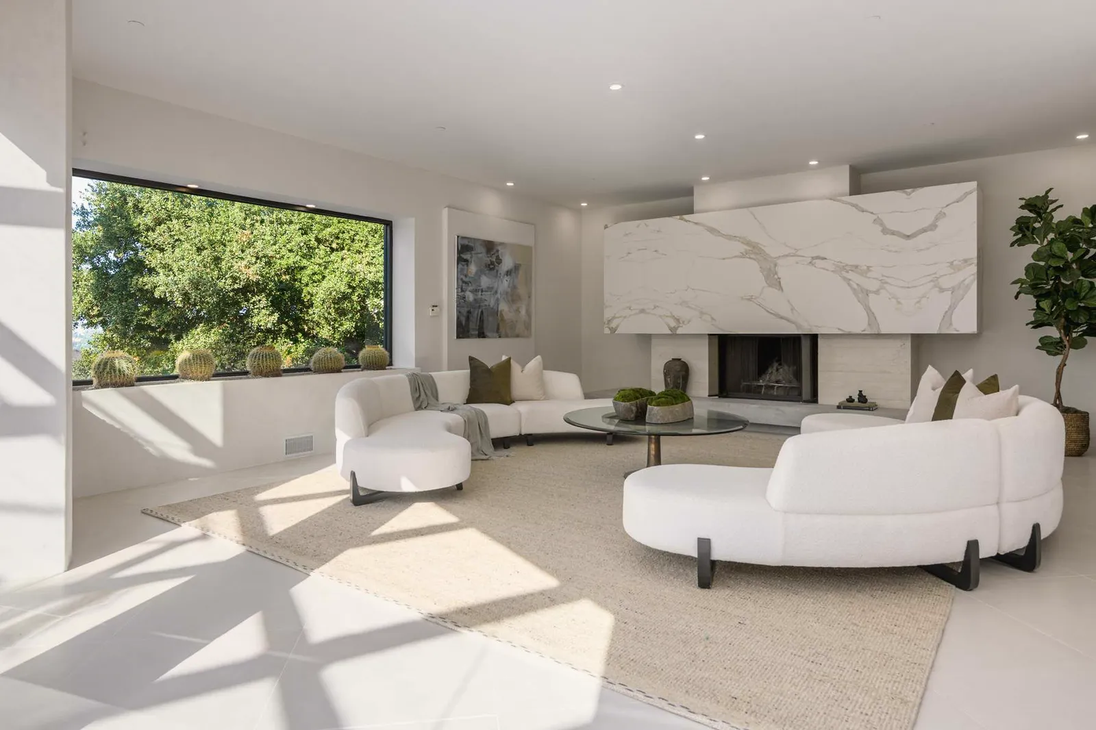Living room with curved white sofas, a marble fireplace wall, and a picture window