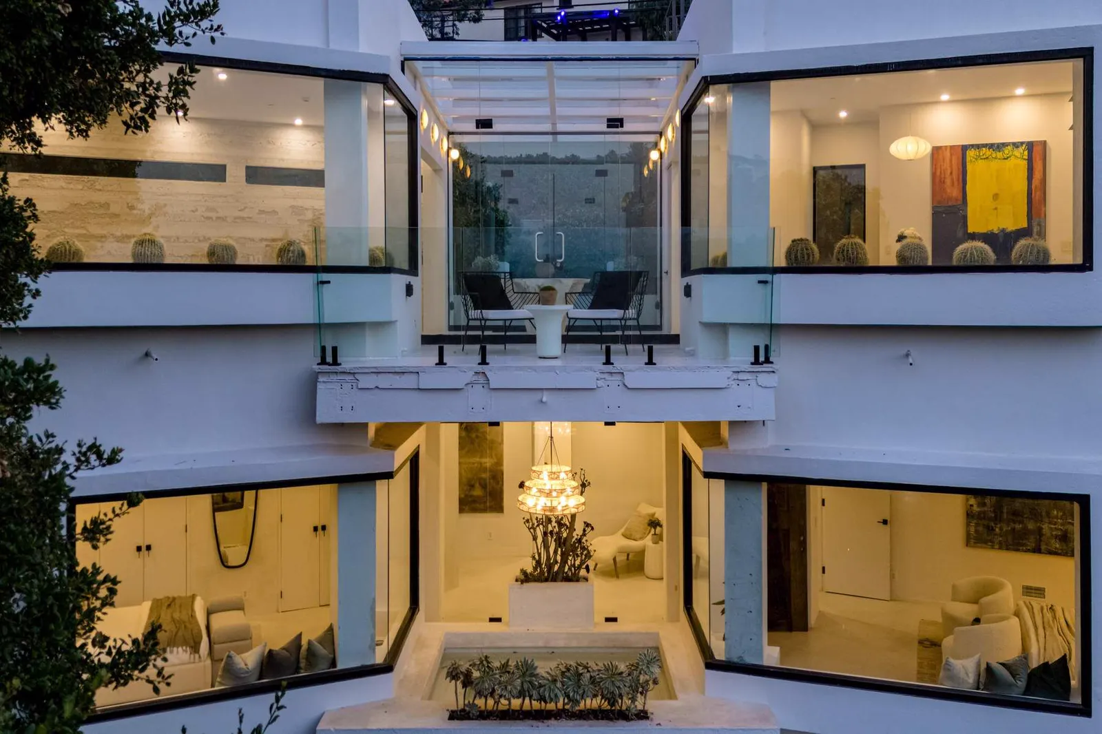 Courtyard view of the house at dusk with lit rooms on two levels