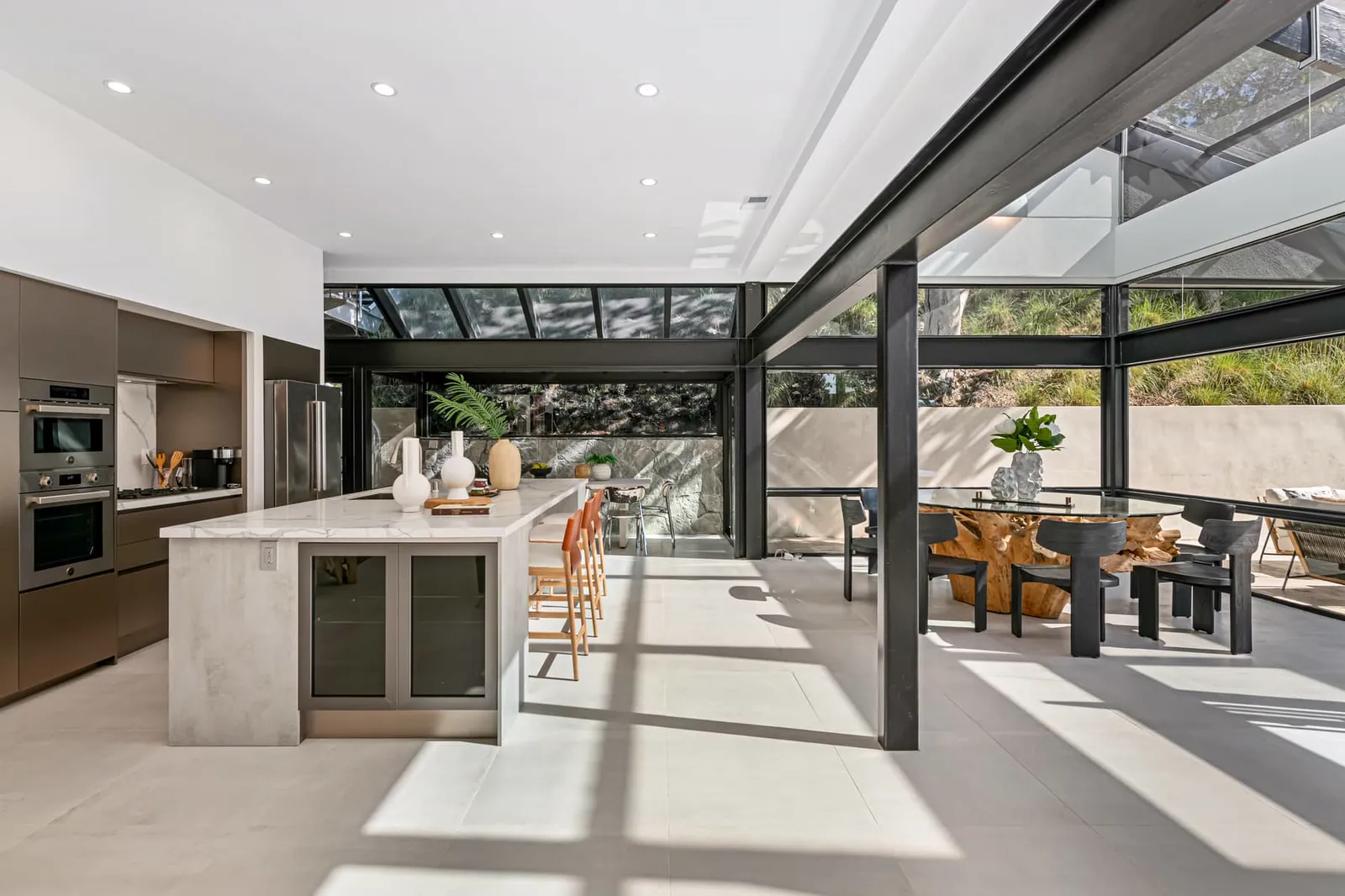 Kitchen island and dining table under a steel and glass roof