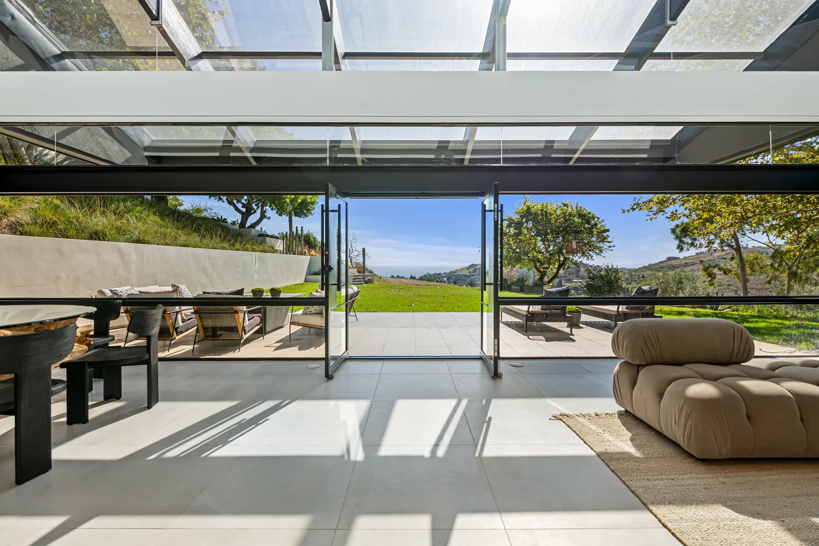Dining area opening fully to the terrace through sliding glass walls