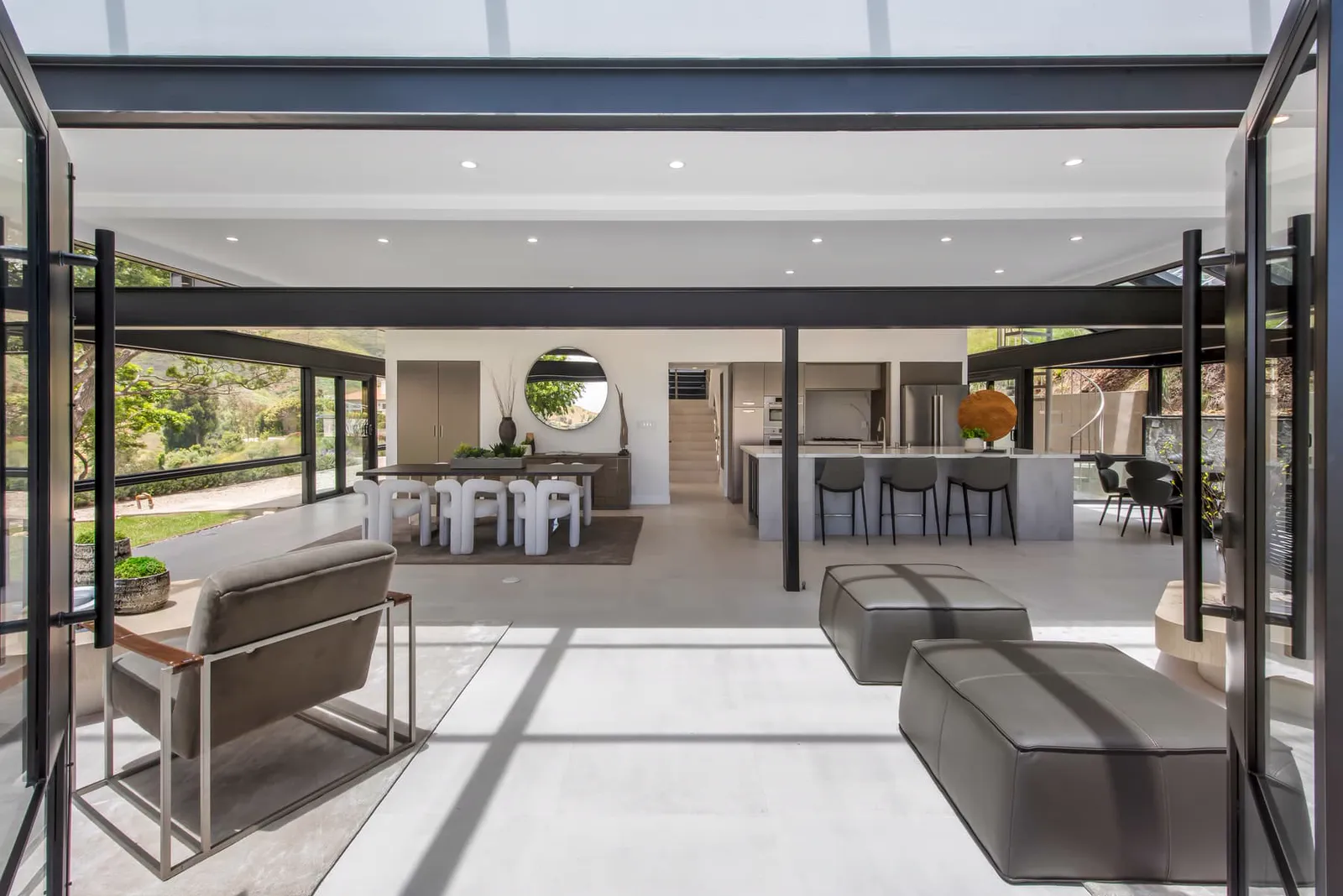 Living room seating with leather ottomans and the kitchen beyond