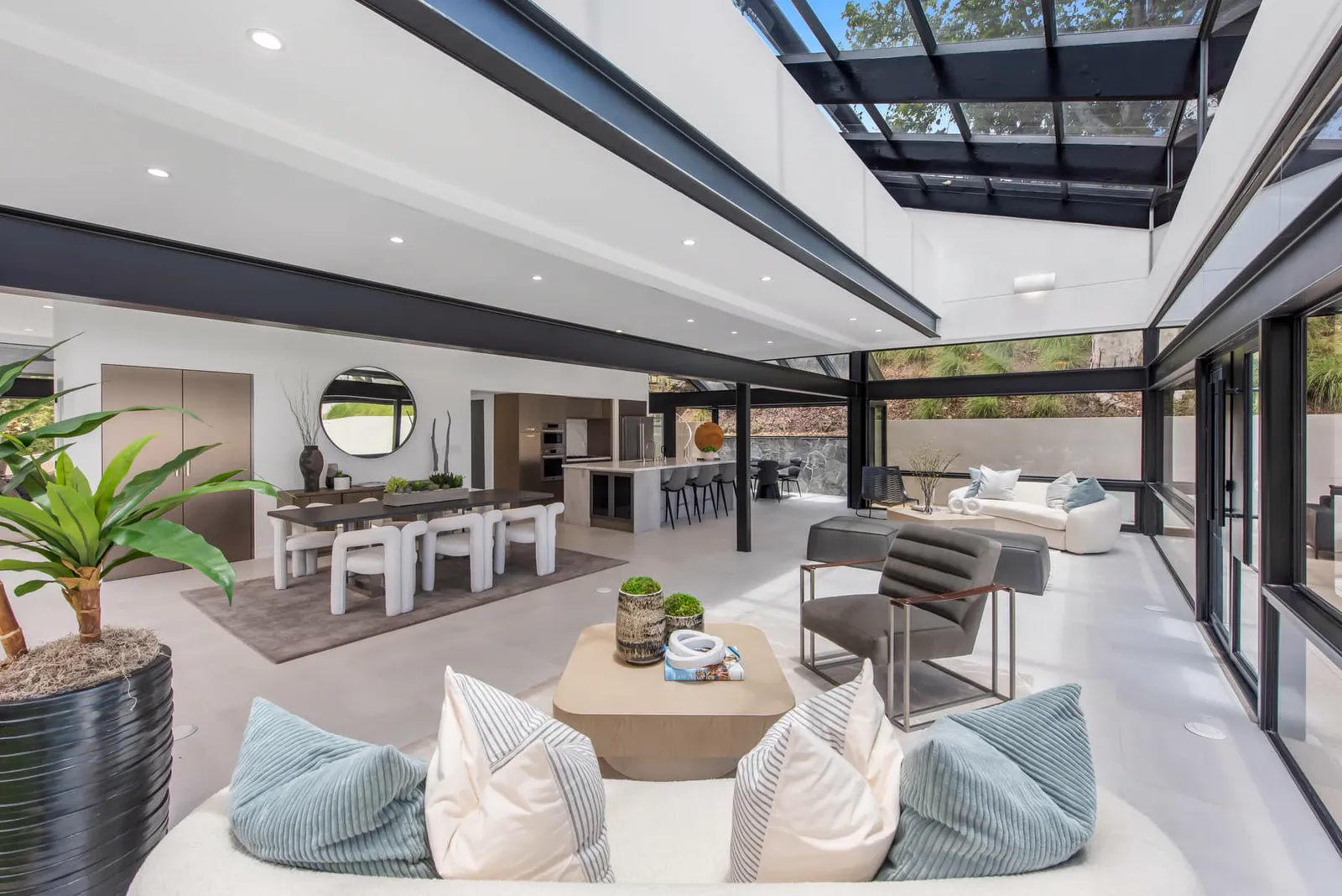 Living area with blue pillows under a skylight roof, with the kitchen beyond
