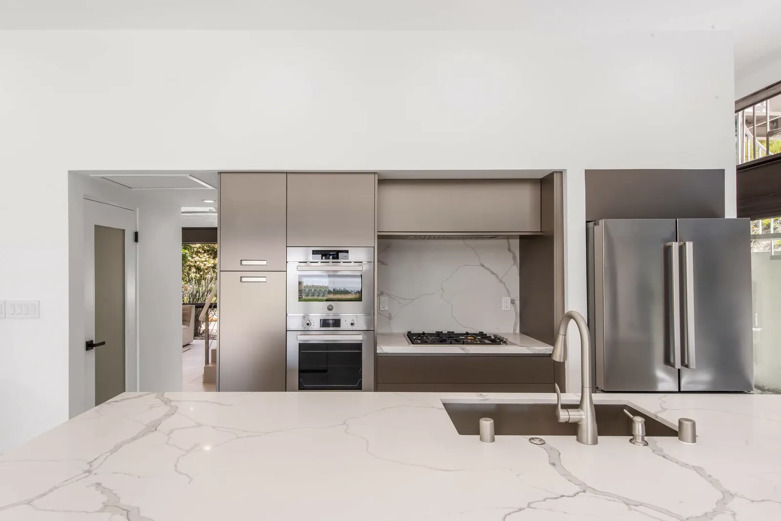 Kitchen sink with a marble counter, wood-tone cabinets, and built-in ovens