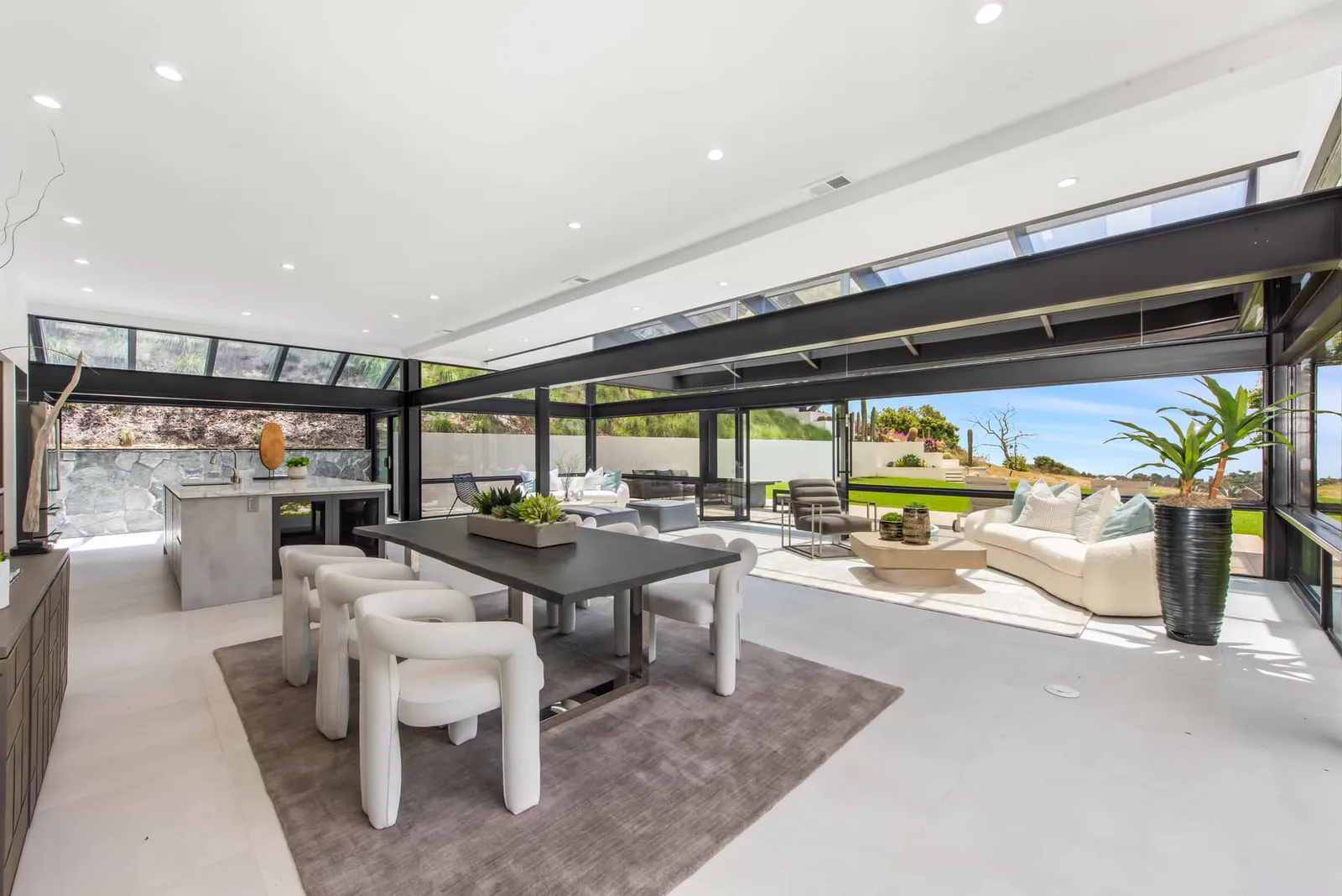 Dining area with white chairs and glass walls to the terrace