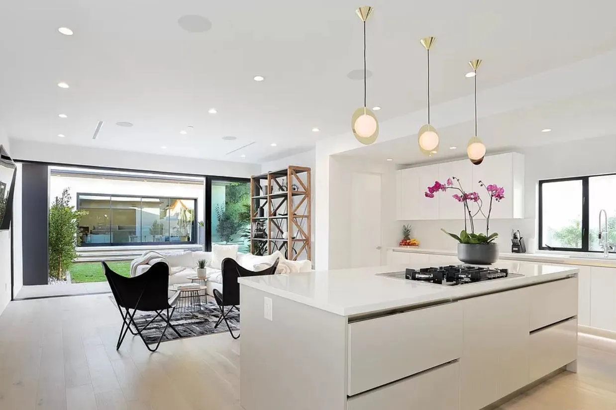 Kitchen island and living area with a sliding glass wall to the garden