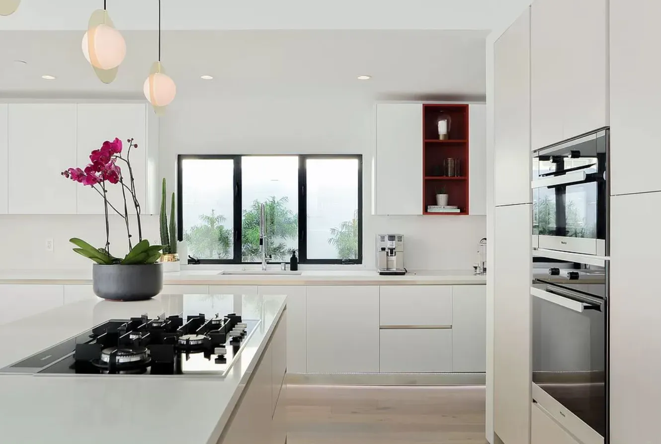 Island cooktop and built-in ovens in a white kitchen