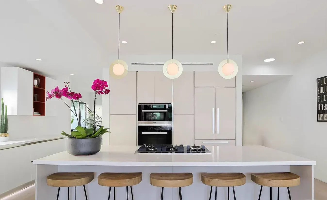 Kitchen island with five stools under three globe pendants