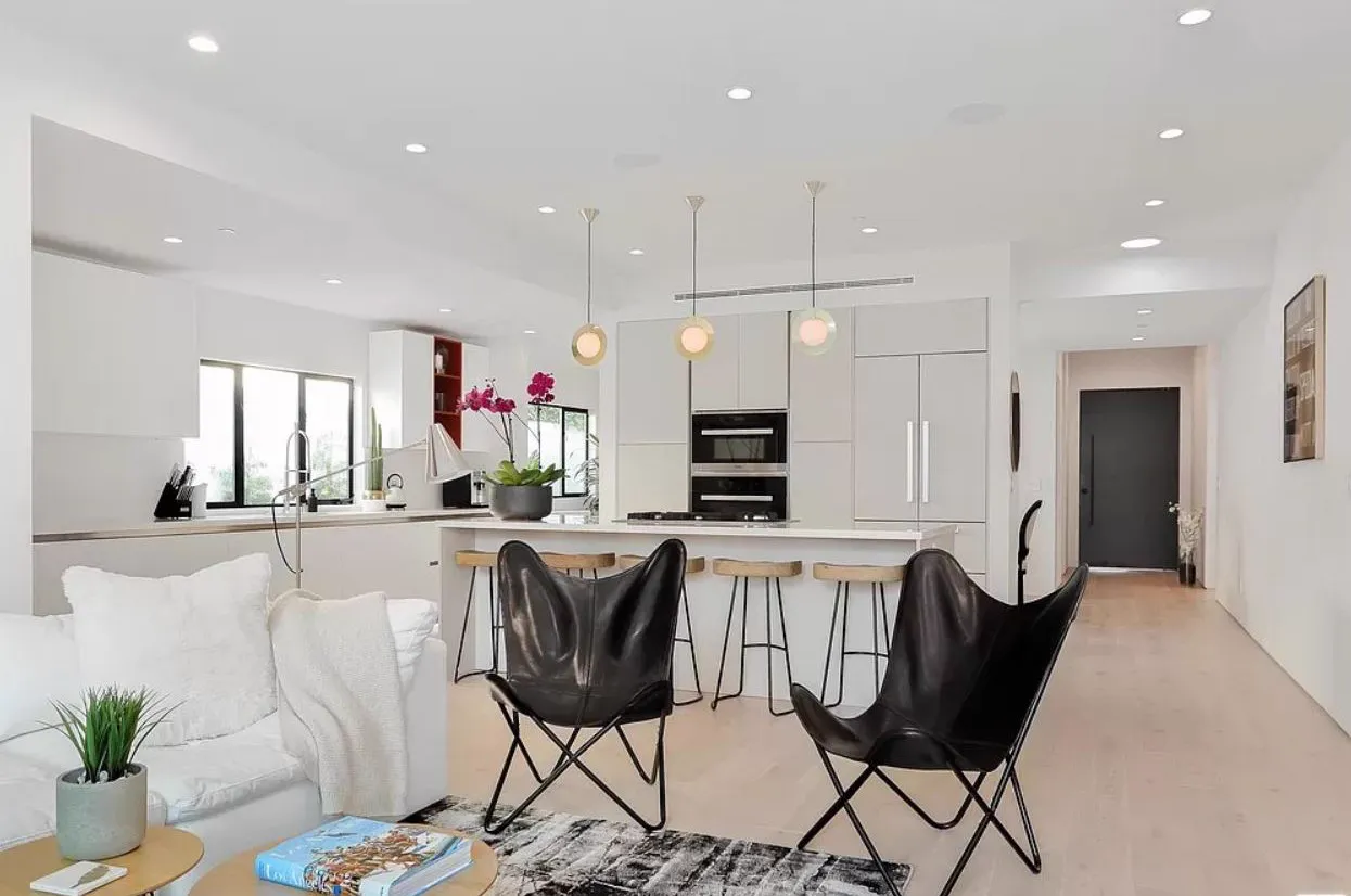 Open living room and kitchen with a white sofa and black sling chairs