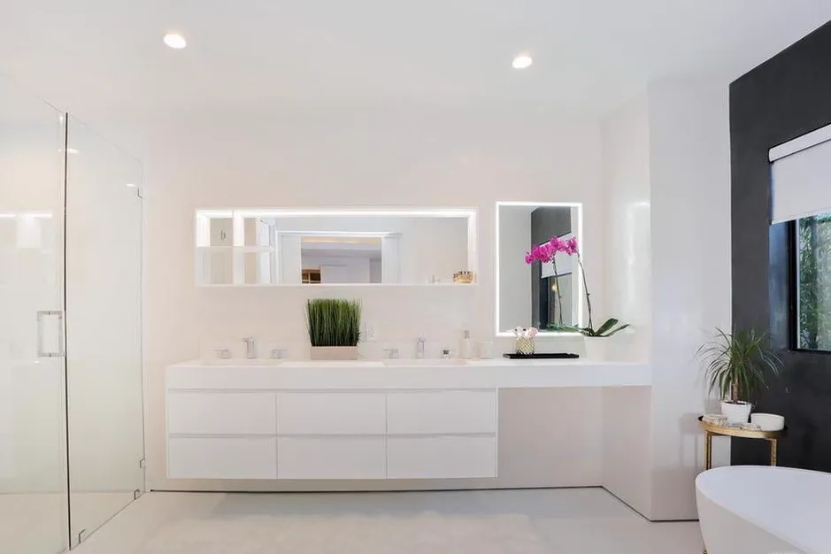 Primary bathroom with a floating double vanity, backlit mirrors, and freestanding tub